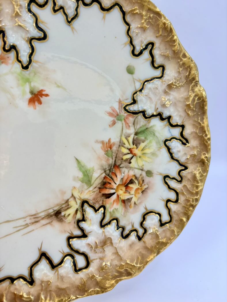 Decorative ceramic plate with floral patterns and gold trim on a light blue background