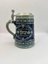 Blue ceramic stein with silver lid on a white background