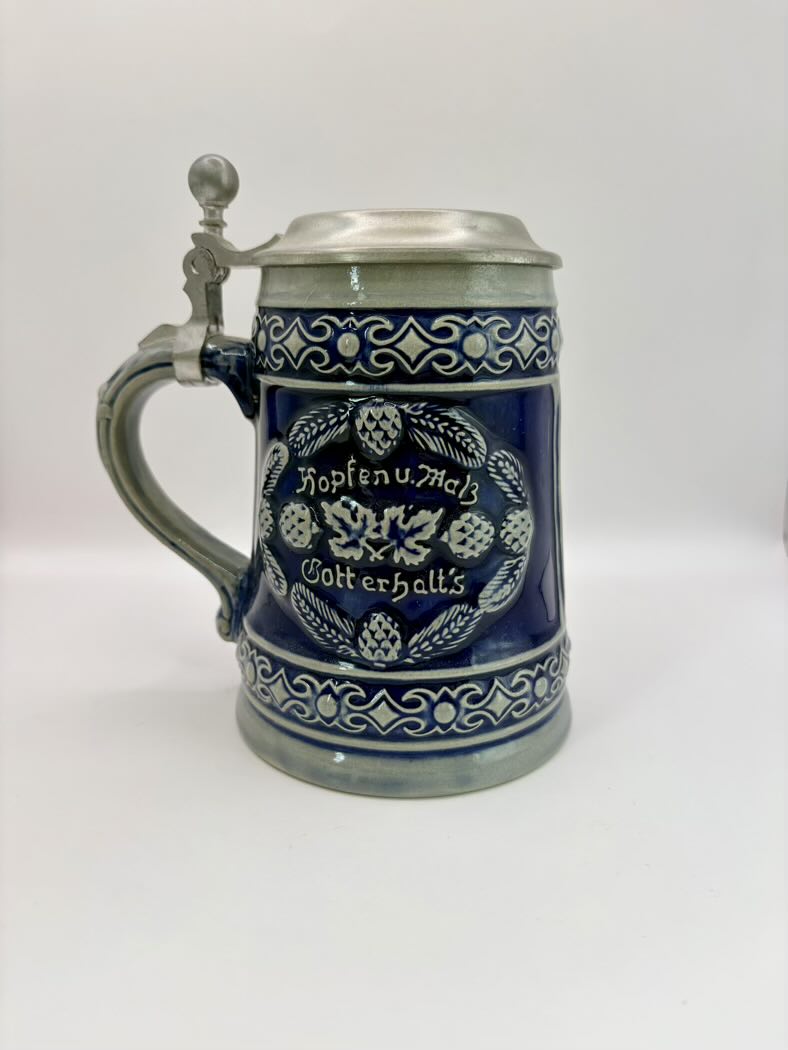 Blue ceramic stein with silver lid on a white background