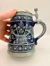 Decorative blue and white ceramic mug with intricate patterns held by a hand on a light background