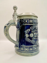 Blue and white ceramic tankard with silver lid on a white background