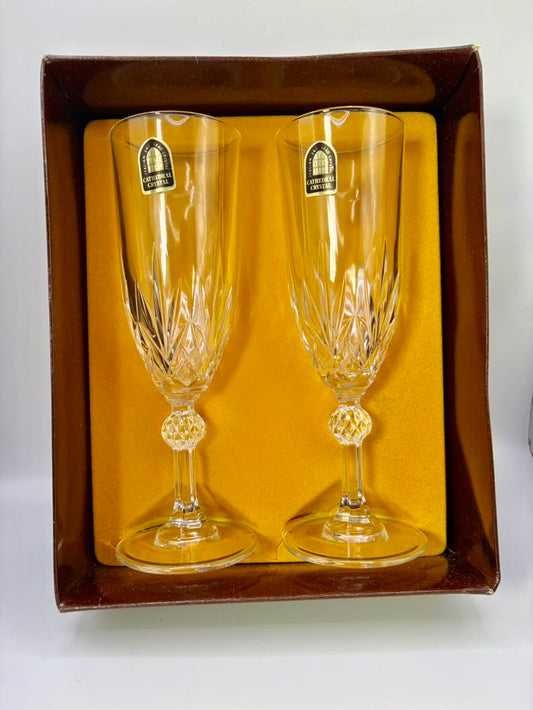 Two crystal champagne flutes in a decorative box with a visible brand label.