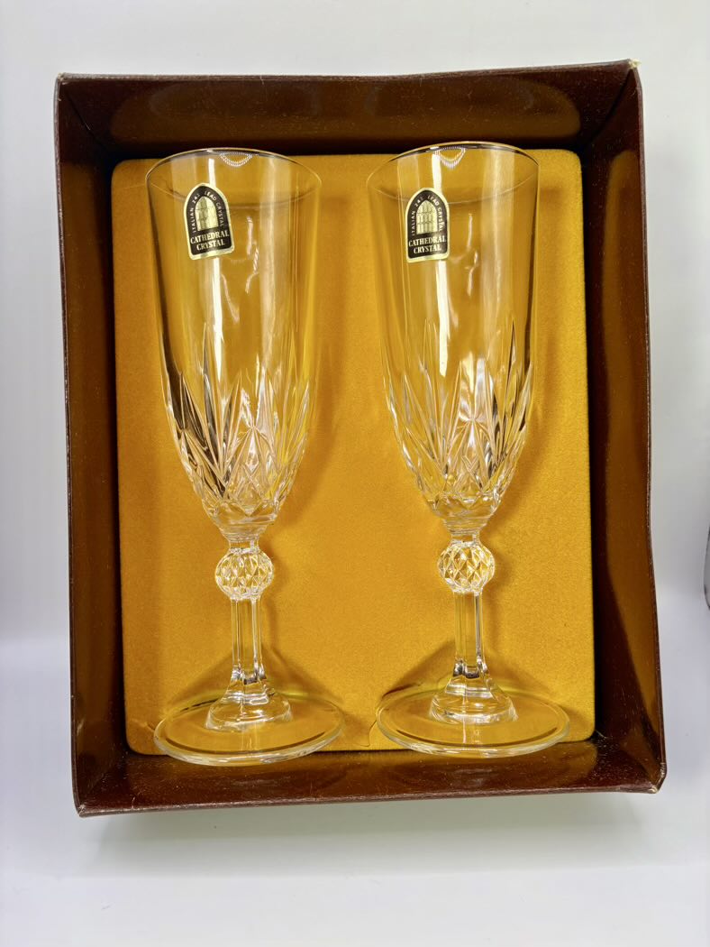 Two crystal champagne flutes in a decorative box with a visible brand label.