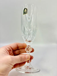 Clear glass flute held by a hand against a plain background