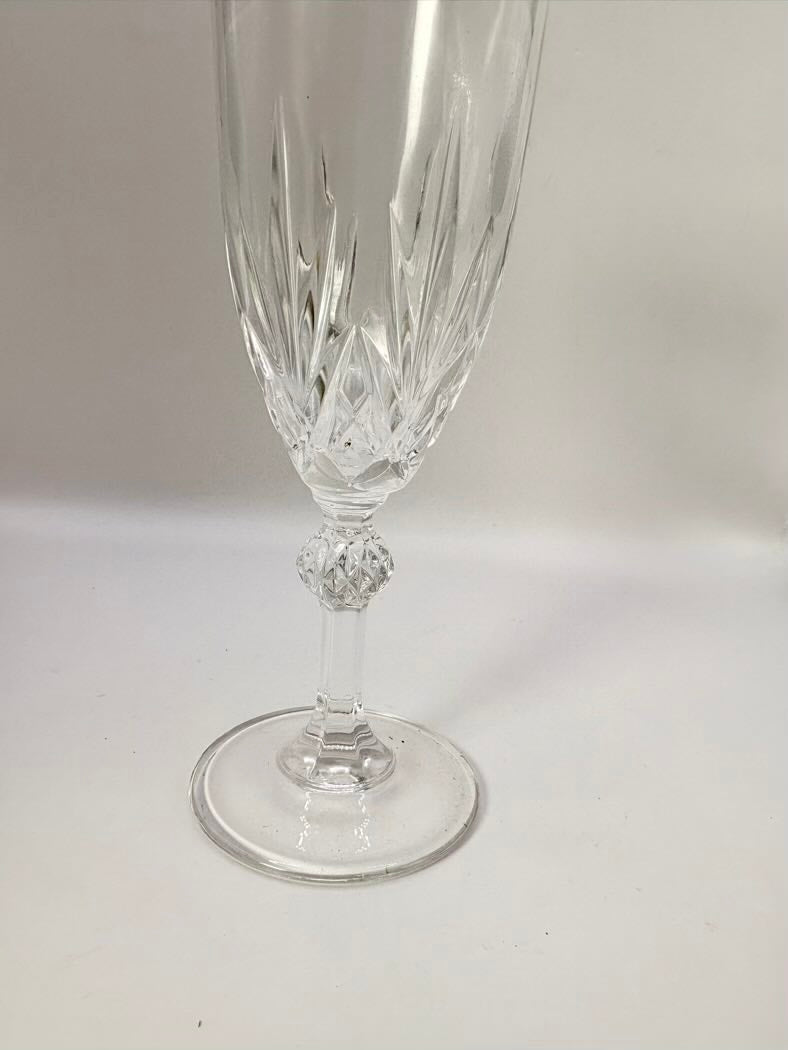 Clear crystal flute with decorative base on a light gray background