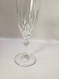 Clear crystal flute with decorative base on a light gray background