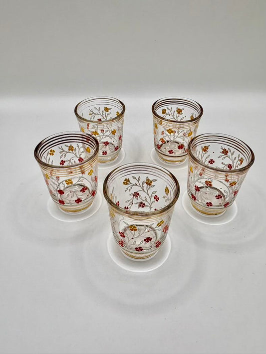 Set of five decorative glass tumblers with floral patterns on a white background