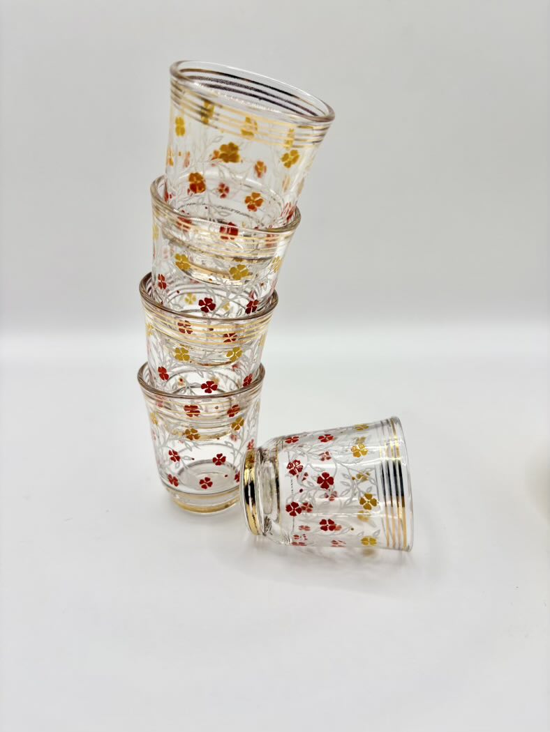 Stack of floral-patterned glass tumblers on a light gray background