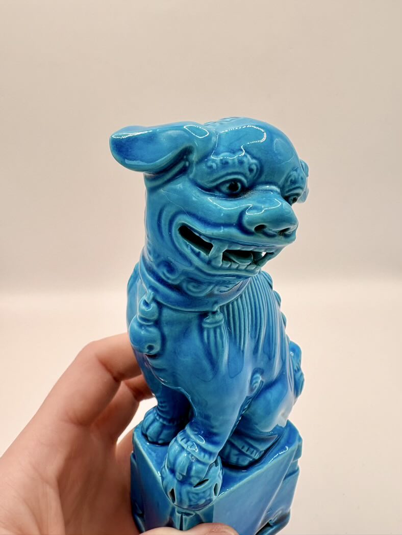 Blue dog statue held in a hand against a beige background