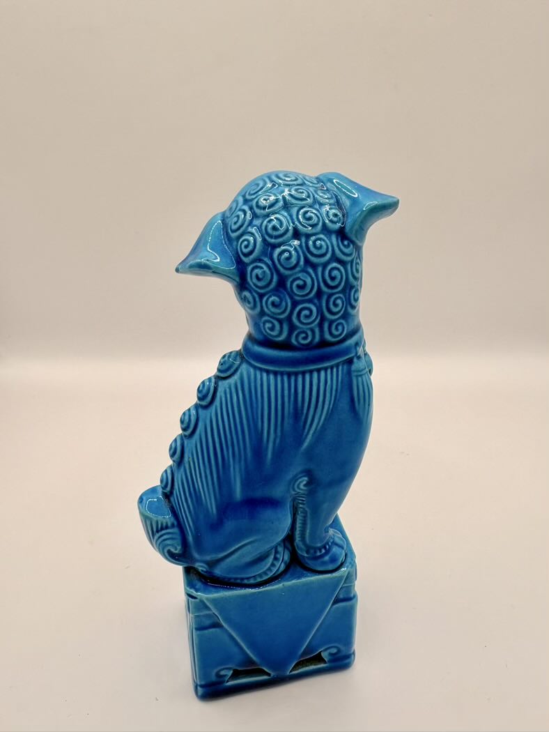 Blue ceramic sculpture of a stylized animal on a beige background