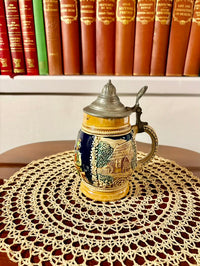 Decorative ceramic stein with lid on a lace doily in front of books