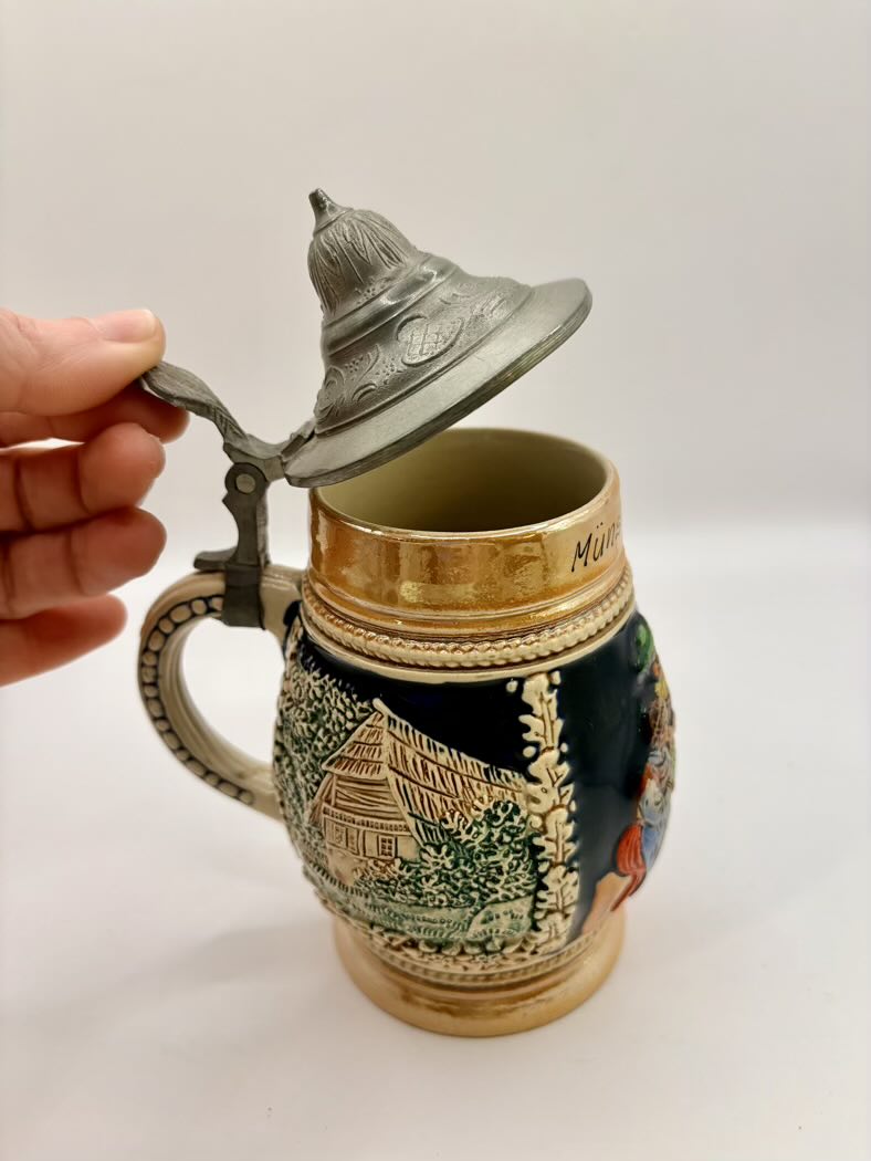 Decorative ceramic mug with lid held by a hand on a white background