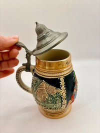 Decorative ceramic mug with lid held by a hand on a white background