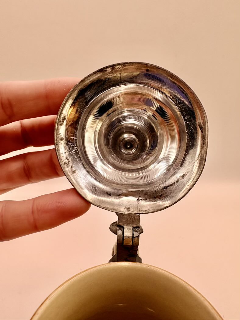 Close-up of a metallic object held by a hand against a beige background