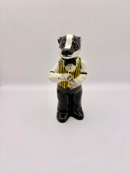 Badger figurine wearing a vest and bow tie on a white background
