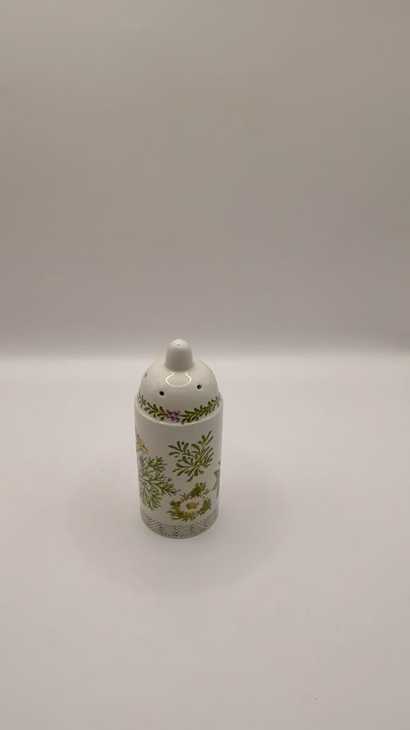 Decorative salt shaker with floral pattern on a white background