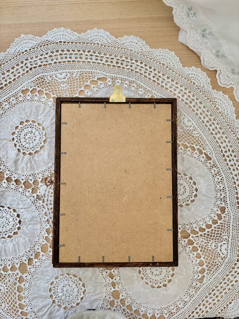 Blank cardboard sheet with a wooden frame on a lace doily