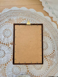 Blank cardboard sheet with a wooden frame on a lace doily
