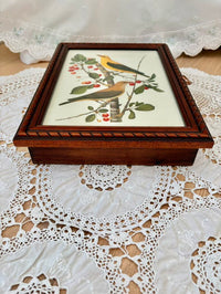 Wooden box with bird and floral design on a lace tablecloth
