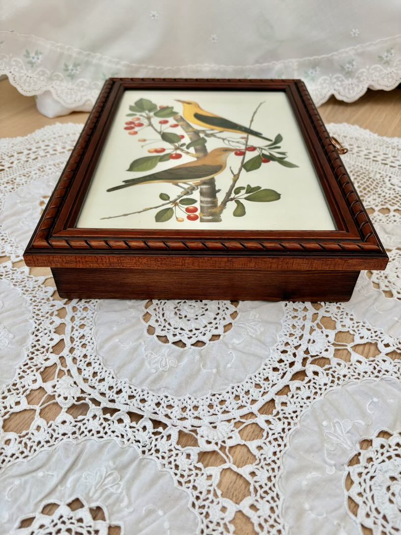Wooden box with bird and floral design on a lace tablecloth