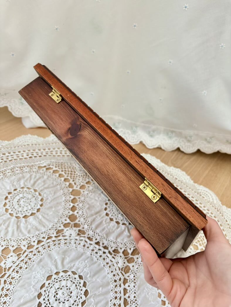 Wooden box held by a hand on a lace tablecloth