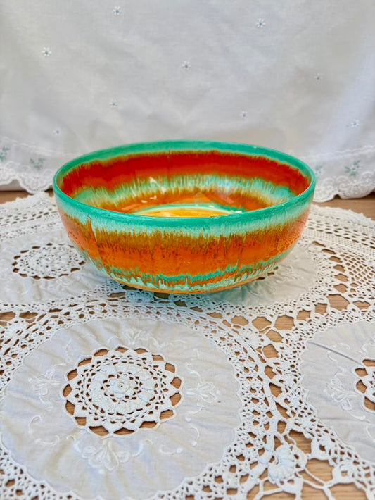 Ceramic bowl with orange and green glaze on a lace doily