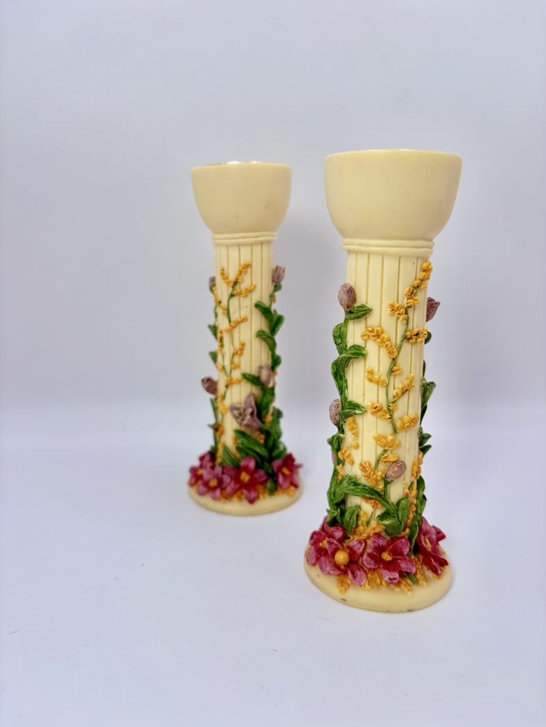 Two decorative candle holders with floral designs on a light gray background