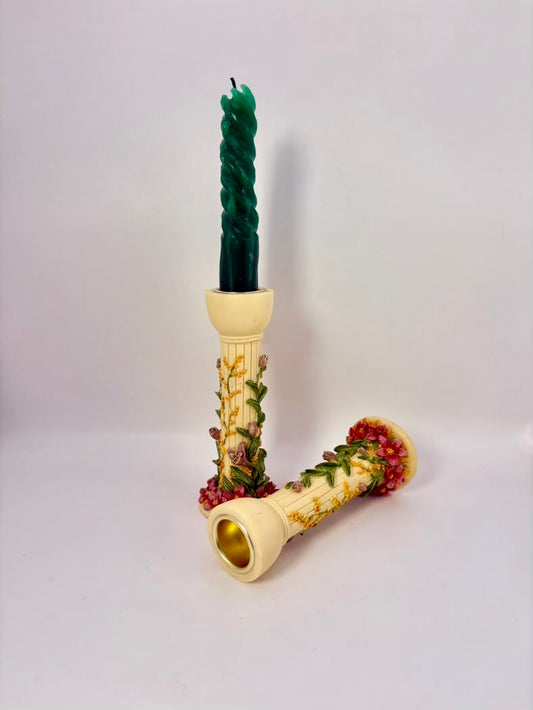 Decorative candle with twisted green top and floral design on a white background