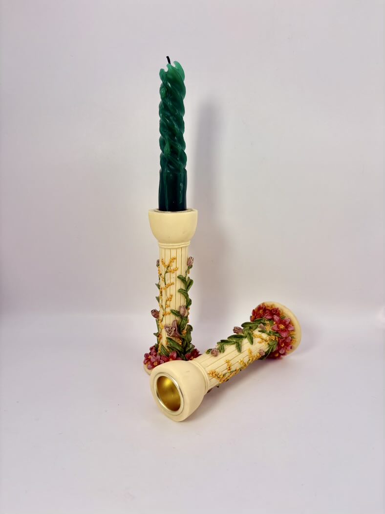 Decorative candle with twisted green top and floral design on a white background