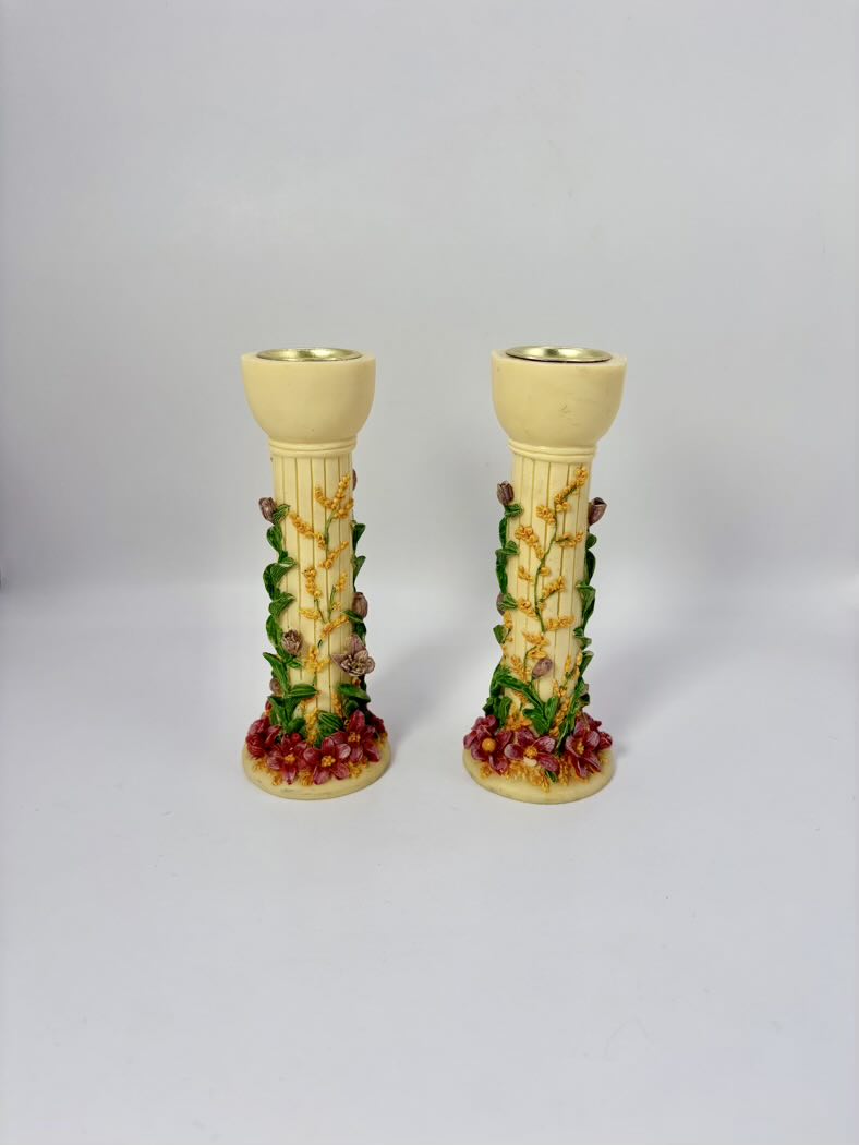 Two decorative candle holders with floral and fruit design on a light gray background