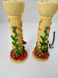 Decorative candle holders with floral and vine designs on a white background