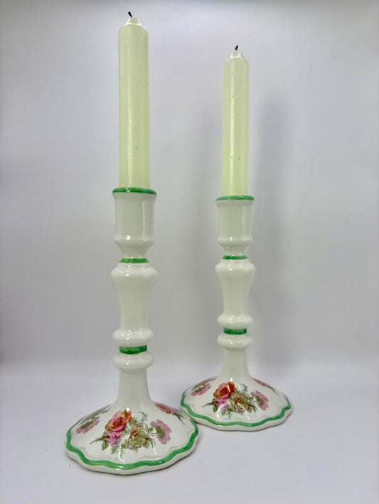 Two floral-patterned candlesticks with candles on a white background