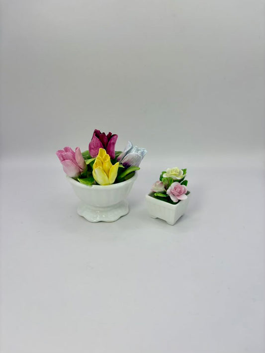 Two small ceramic flower pots with colorful flowers on a white background