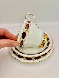 Teacup with gold and brown leaf patterns on a white background