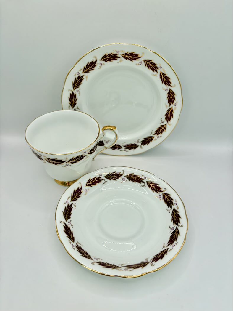 Tea cup, saucer, and plate set with decorative brown patterns on a white background