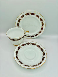 Tea cup, saucer, and plate set with decorative brown patterns on a white background