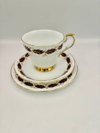 Tea cup and saucer set with gold and brown leaf design on a white background