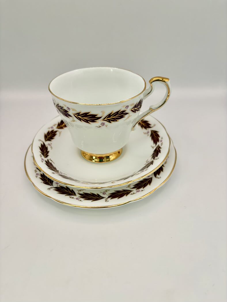 Tea cup and saucer set with gold and brown leaf design on a white background