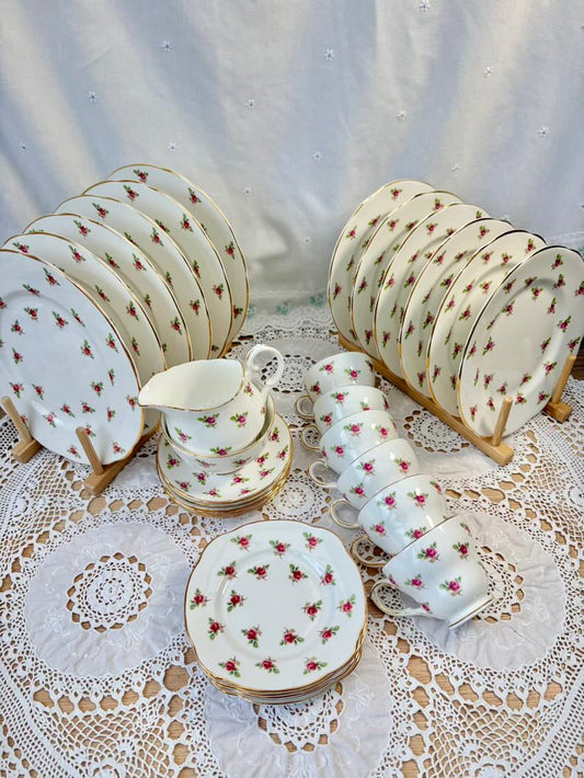 Ceramic tableware set with floral patterns on a lace tablecloth.