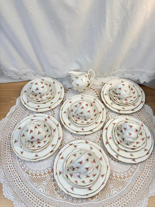 Set of ceramic tea sets on a lace doily with a white curtain background