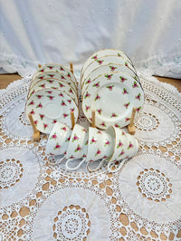 Set of ceramic teacups and saucers with floral design on a lace tablecloth.