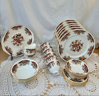 Set of ceramic dishes with floral patterns on a lace tablecloth.