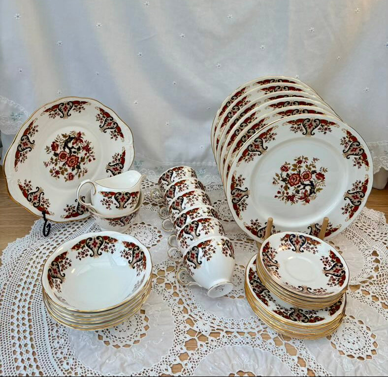 Set of ceramic dishes with floral patterns on a lace tablecloth.