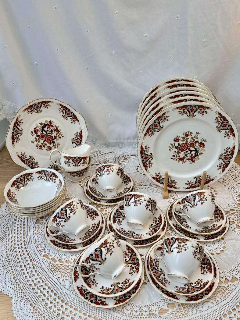 Set of ceramic dishes with floral patterns on a lace tablecloth.