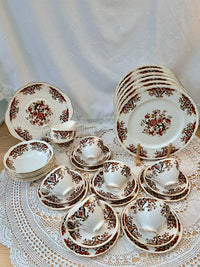 Set of ceramic dishes with floral patterns on a lace tablecloth.