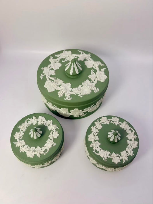 Set of three green ceramic jars with white floral patterns on a white background