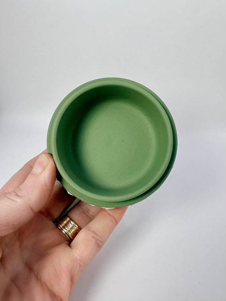 Green ceramic bowl held in a hand against a white background
