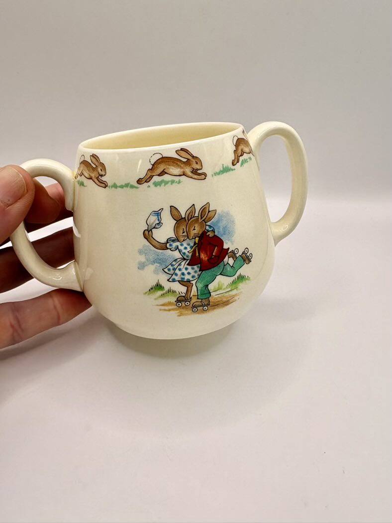Ceramic mug with rabbit design held by a hand on a white background