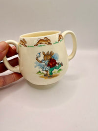 Ceramic mug with rabbit design held by a hand on a white background