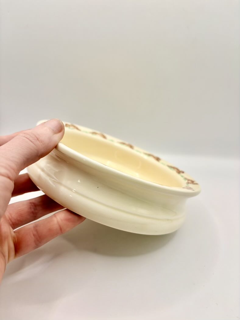 Hand holding a small ceramic bowl against a plain background